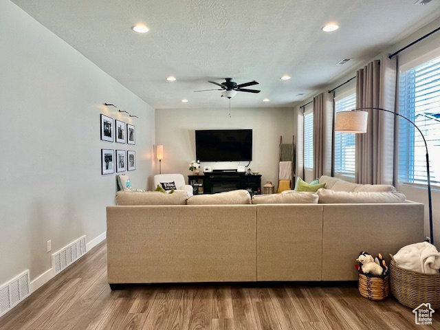 Living room with ceiling fan, a textured ceiling, a healthy amount of sunlight, and hardwood / wood-style flooring