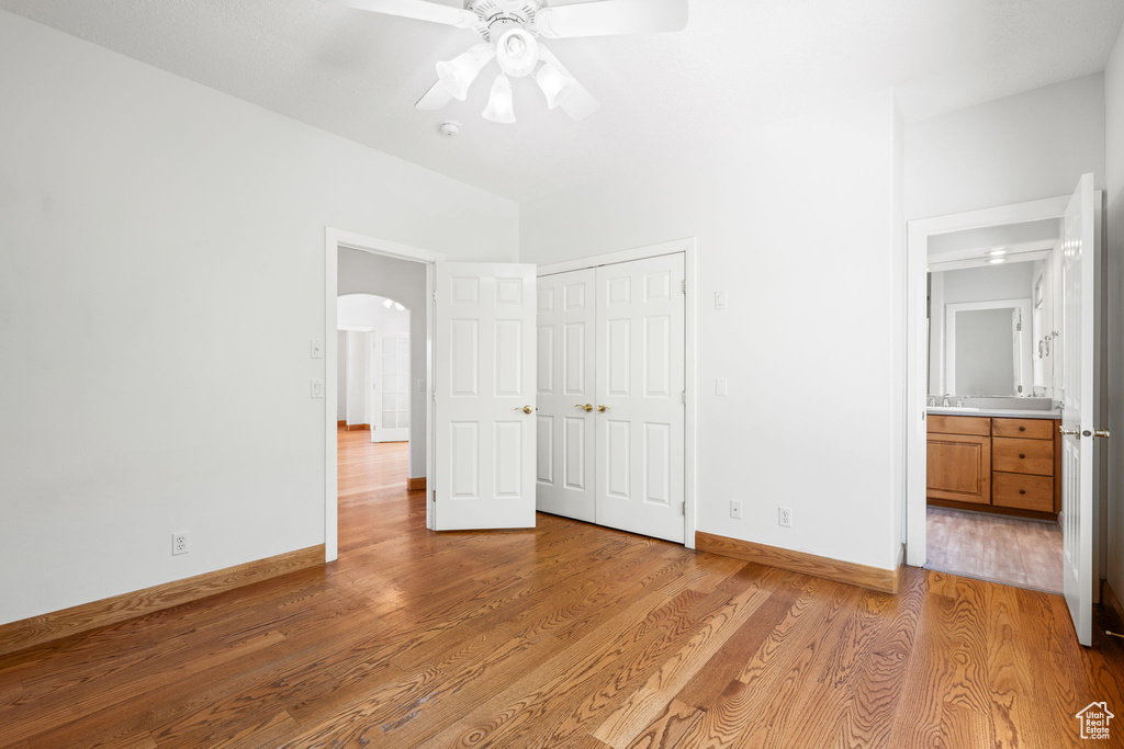 Unfurnished bedroom featuring ceiling fan, light hardwood / wood-style floors, ensuite bath, sink, and a closet