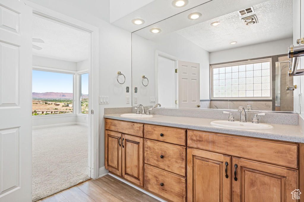 Bathroom with dual vanity, wood-type flooring, and a textured ceiling