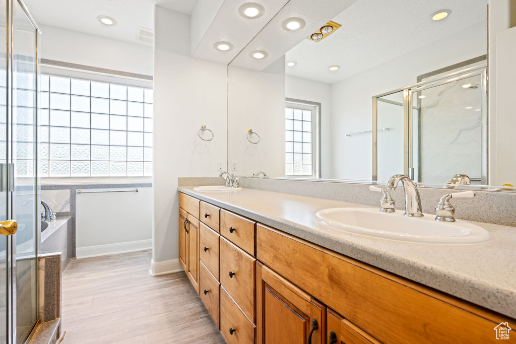 Bathroom with dual vanity, a bathtub, and hardwood / wood-style floors