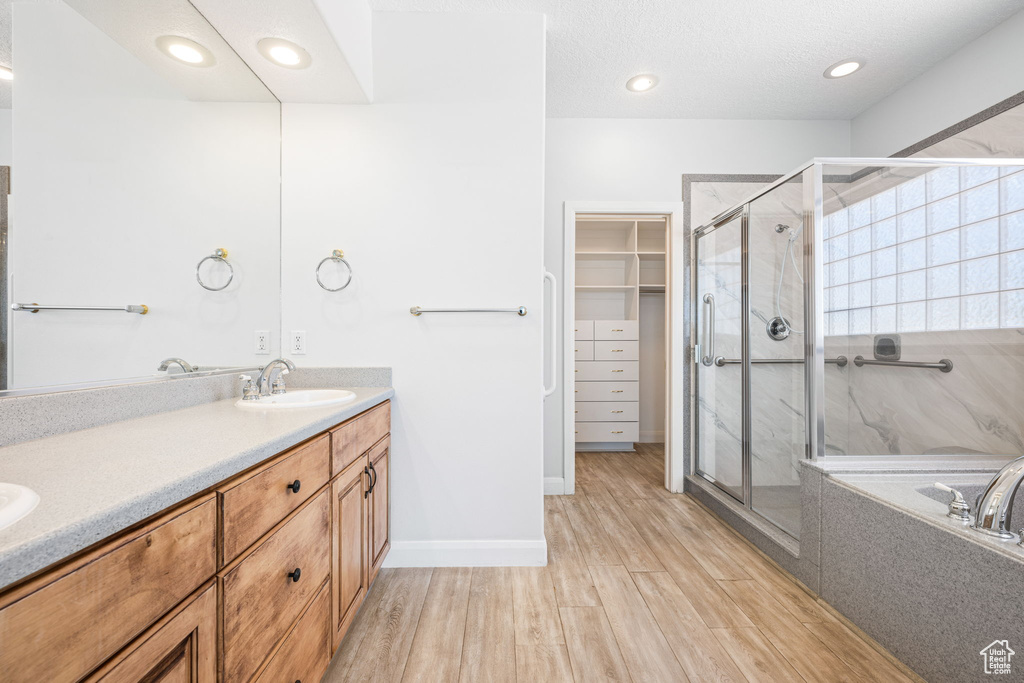 Bathroom featuring dual bowl vanity, plus walk in shower, and hardwood / wood-style flooring