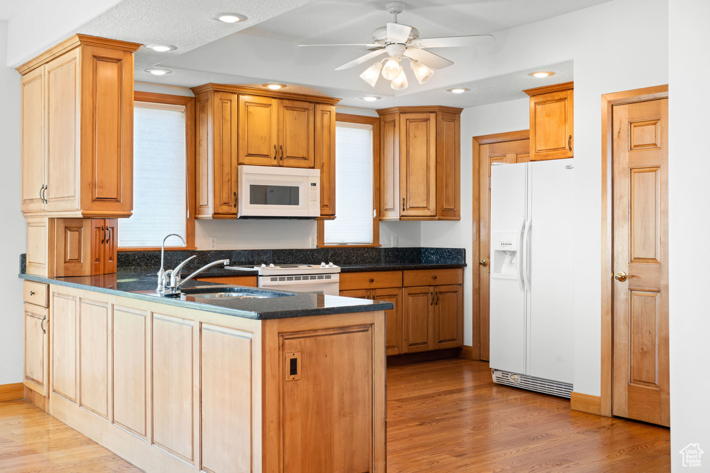 Kitchen featuring ceiling fan, white appliances, light hardwood / wood-style flooring, and kitchen peninsula