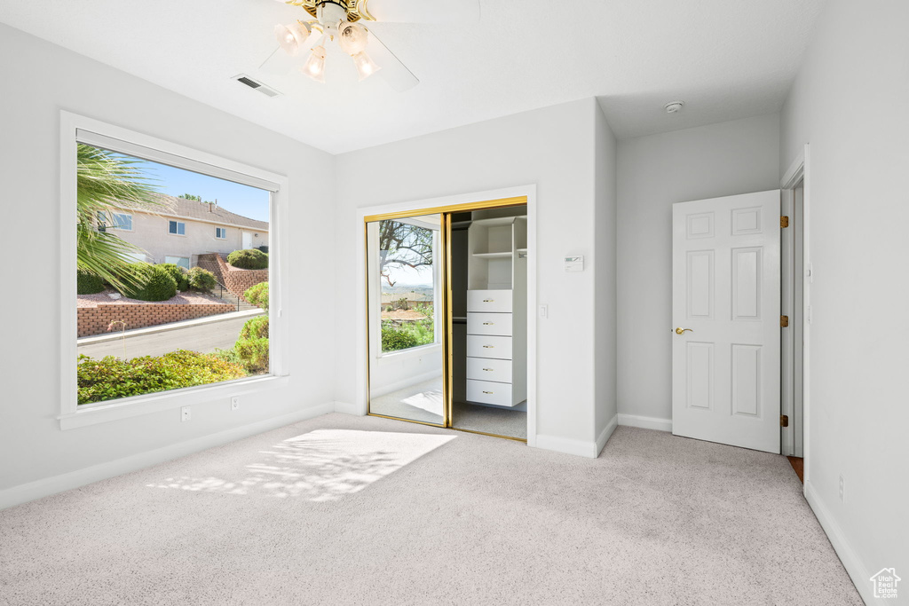 Unfurnished bedroom with light colored carpet, multiple windows, and a closet