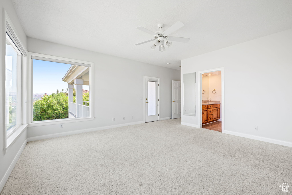 Unfurnished bedroom with ensuite bathroom, ceiling fan, sink, and carpet flooring