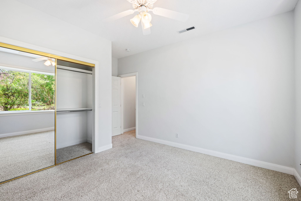 Unfurnished bedroom featuring light carpet, a closet, and ceiling fan