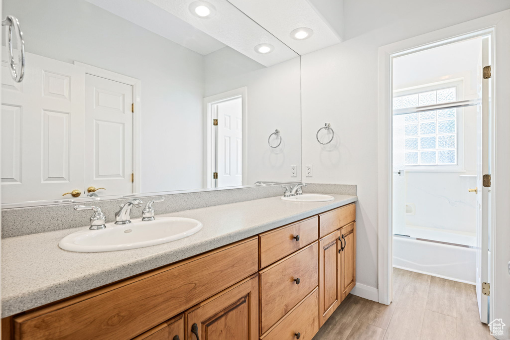 Bathroom featuring dual bowl vanity, wood-type flooring, and shower / washtub combination