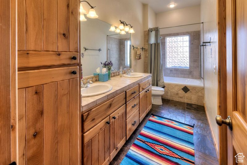 Bathroom with dual vanity, tile patterned floors, and toilet