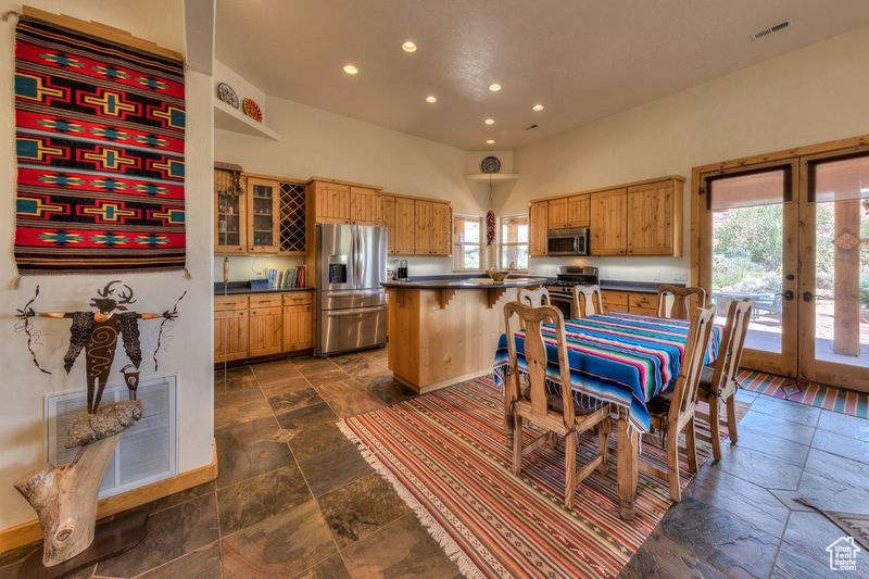 Kitchen with appliances with stainless steel finishes, french doors, and dark tile patterned flooring