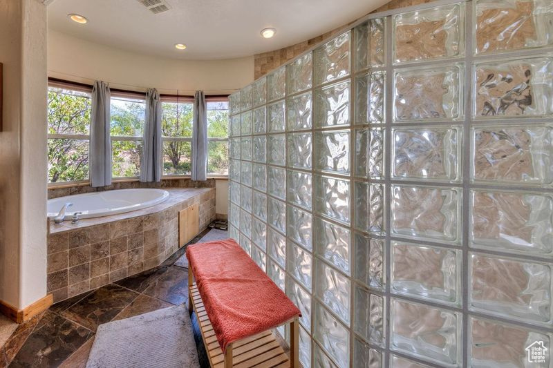 Bathroom with tiled tub and tile patterned flooring