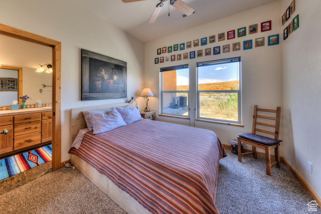 Carpeted bedroom with ensuite bath and ceiling fan