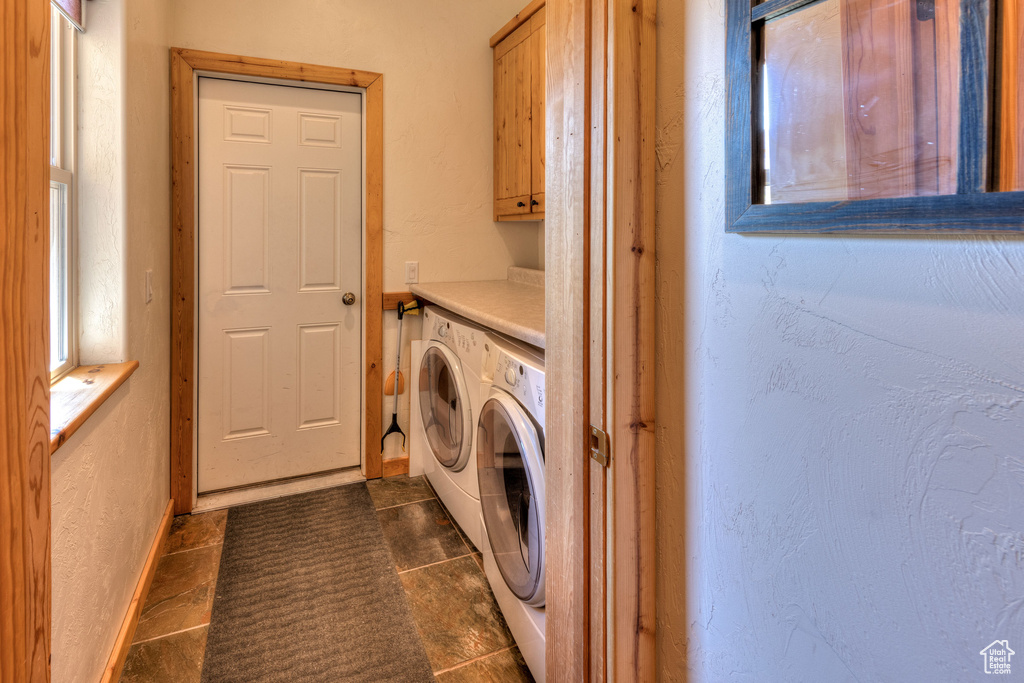 Laundry room with cabinets, dark tile patterned flooring, and separate washer and dryer