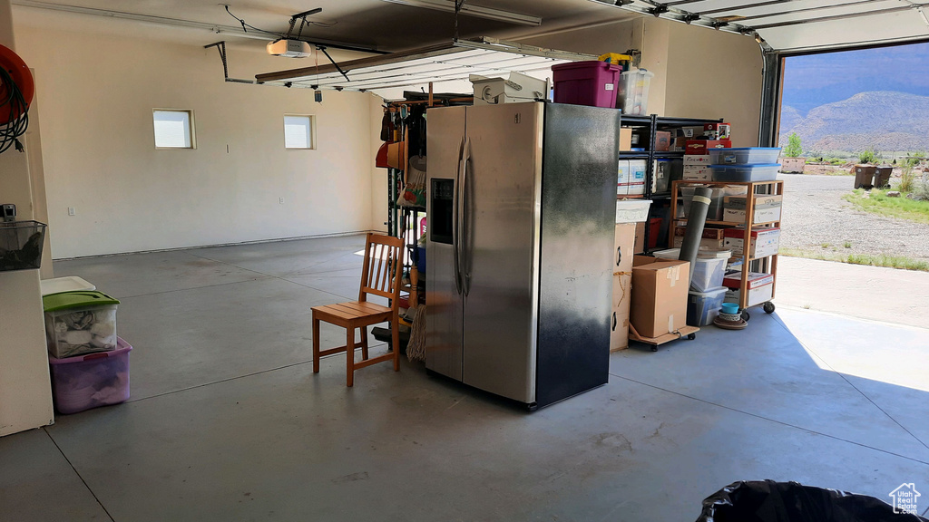 Garage with a garage door opener and stainless steel fridge with ice dispenser