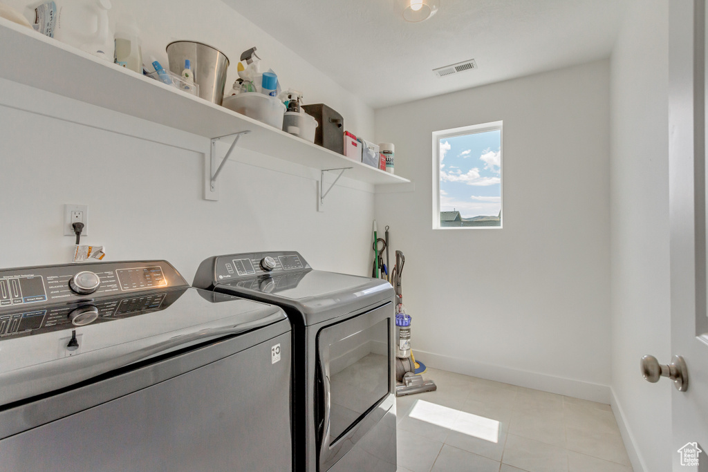 Clothes washing area with independent washer and dryer and light tile patterned floors