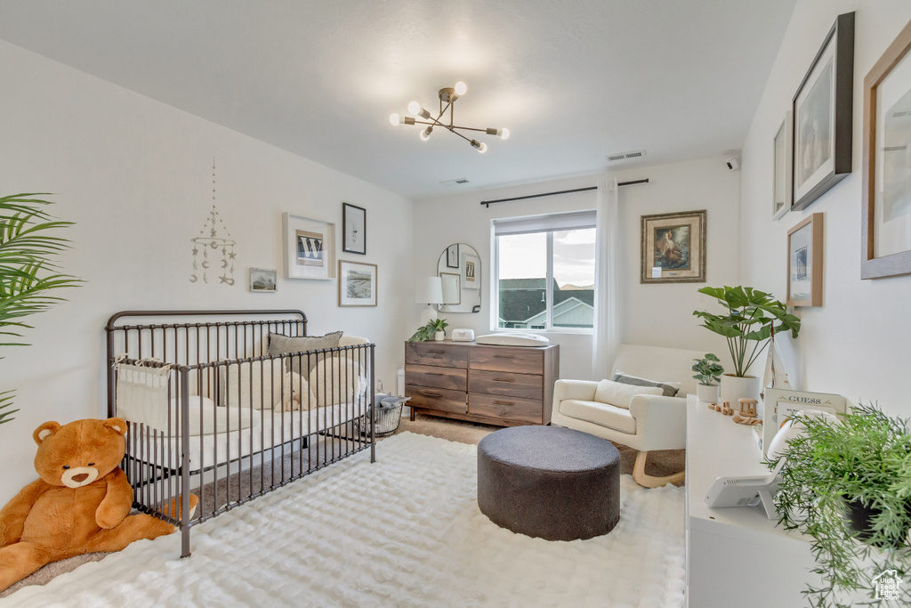 Carpeted bedroom with a crib and a notable chandelier