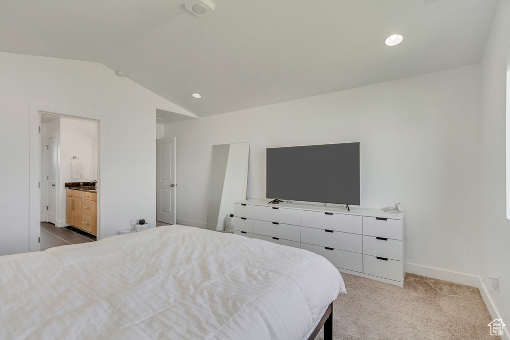 Bedroom with light carpet, lofted ceiling, and ensuite bathroom