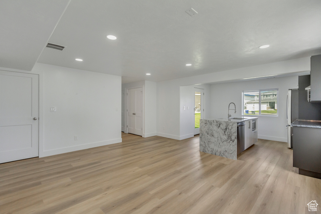 Kitchen featuring light hardwood / wood-style flooring, stainless steel appliances, and a kitchen island with sink