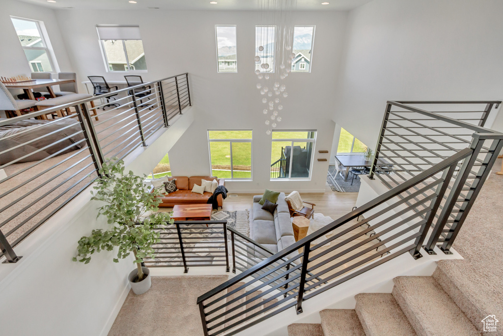 Interior space featuring a notable chandelier, light wood-type flooring, and a towering ceiling