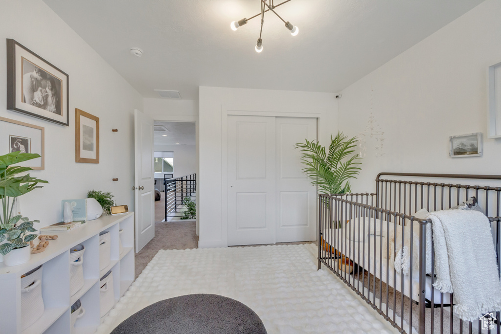 Carpeted bedroom with a closet and a chandelier