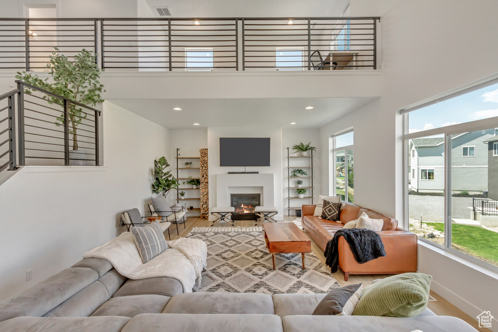 Living room featuring a high ceiling, wood-type flooring, and a wealth of natural light