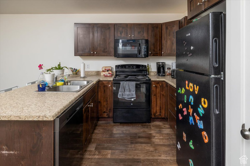 Kitchen with black appliances, dark brown cabinets, and dark hardwood / wood-style floors