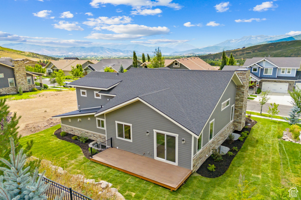 Back of house with a lawn, a deck with mountain view, and a garage