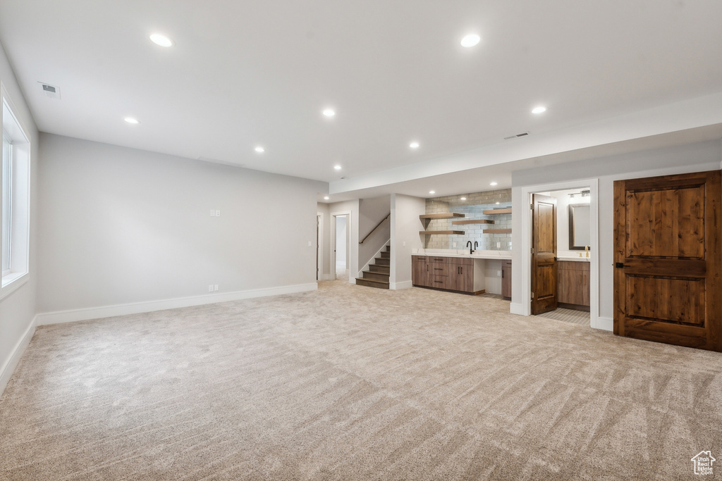 Unfurnished living room with sink and light colored carpet