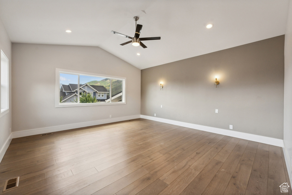 Empty room with ceiling fan, vaulted ceiling, and hardwood / wood-style flooring