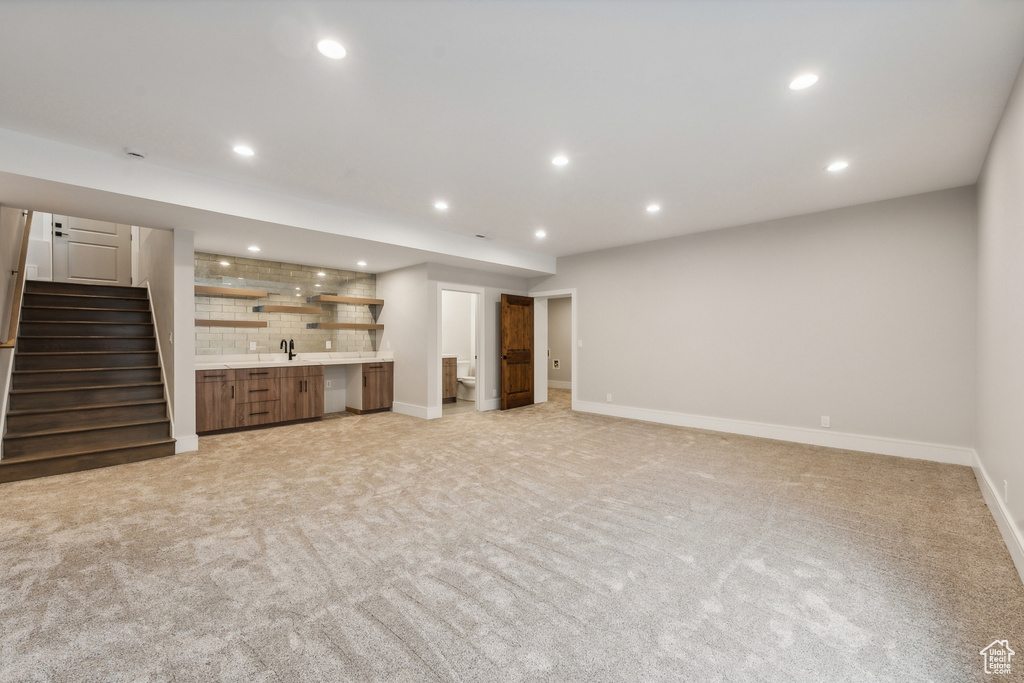 Unfurnished living room with sink and light colored carpet