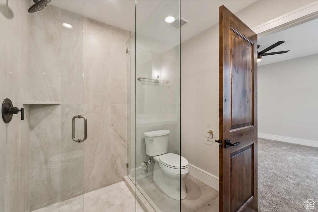 Bathroom with a shower with door, toilet, and ceiling fan