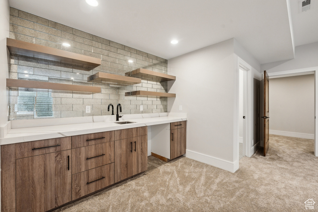 Bar featuring backsplash, sink, and light colored carpet