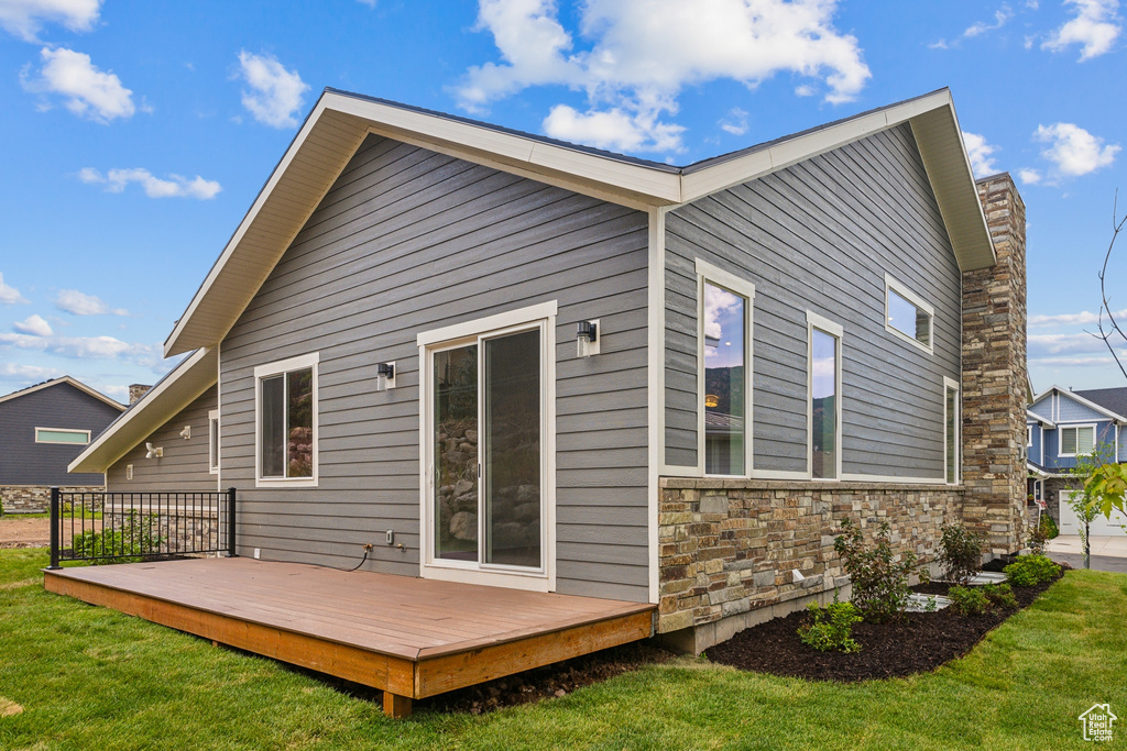 Back of house featuring a wooden deck and a lawn