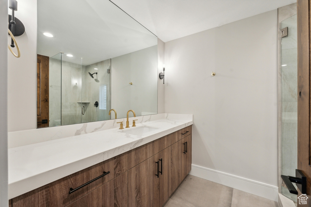 Bathroom with an enclosed shower, vanity, and tile patterned flooring