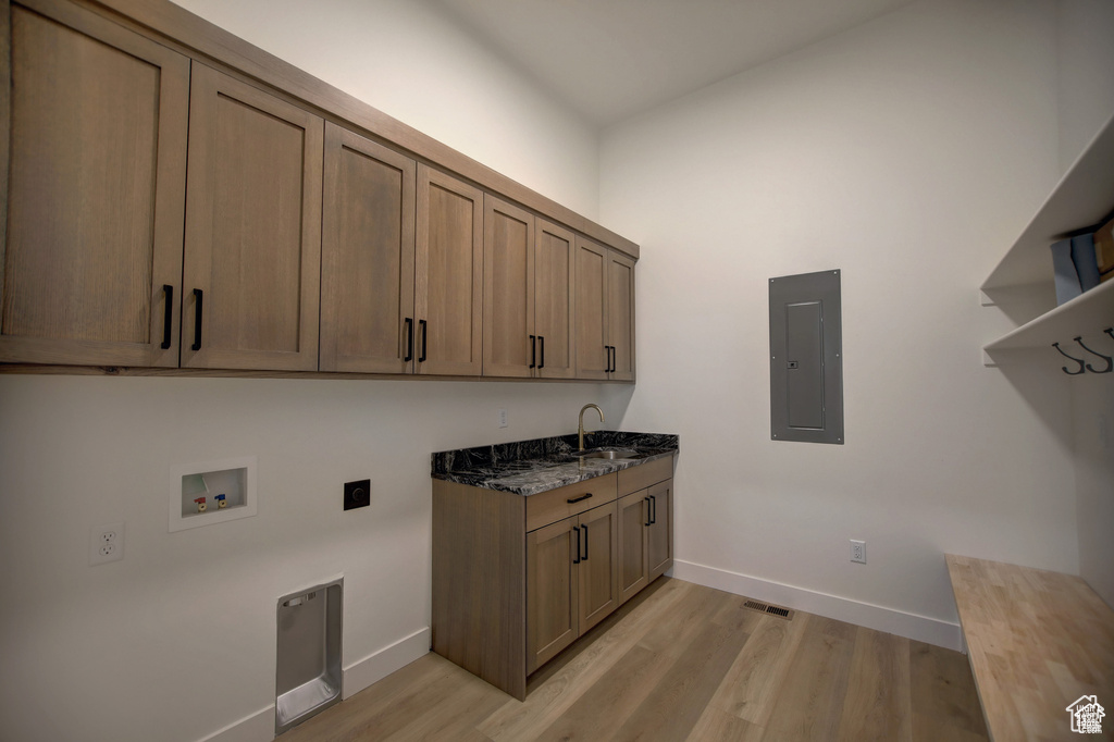 Laundry room featuring cabinets, electric dryer hookup, electric panel, light hardwood / wood-style flooring, and sink