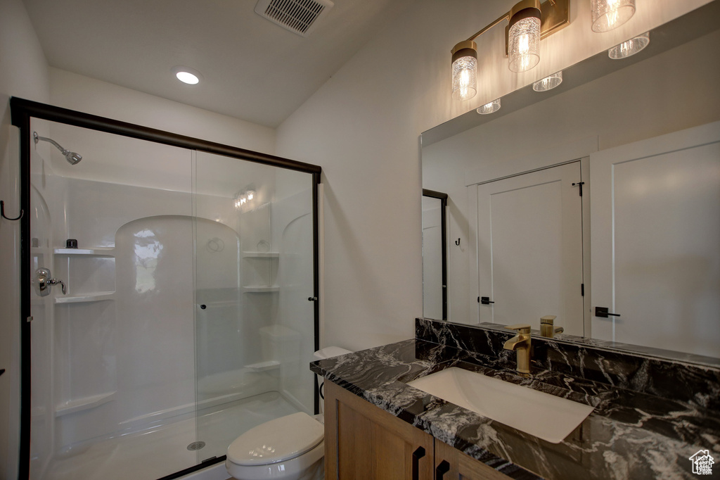 Bathroom with a shower with door, toilet, and vanity