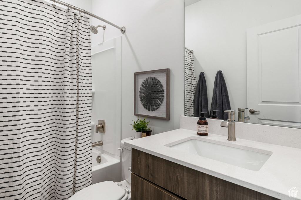 Full bathroom with shower / bath combo with shower curtain, vanity, and toilet