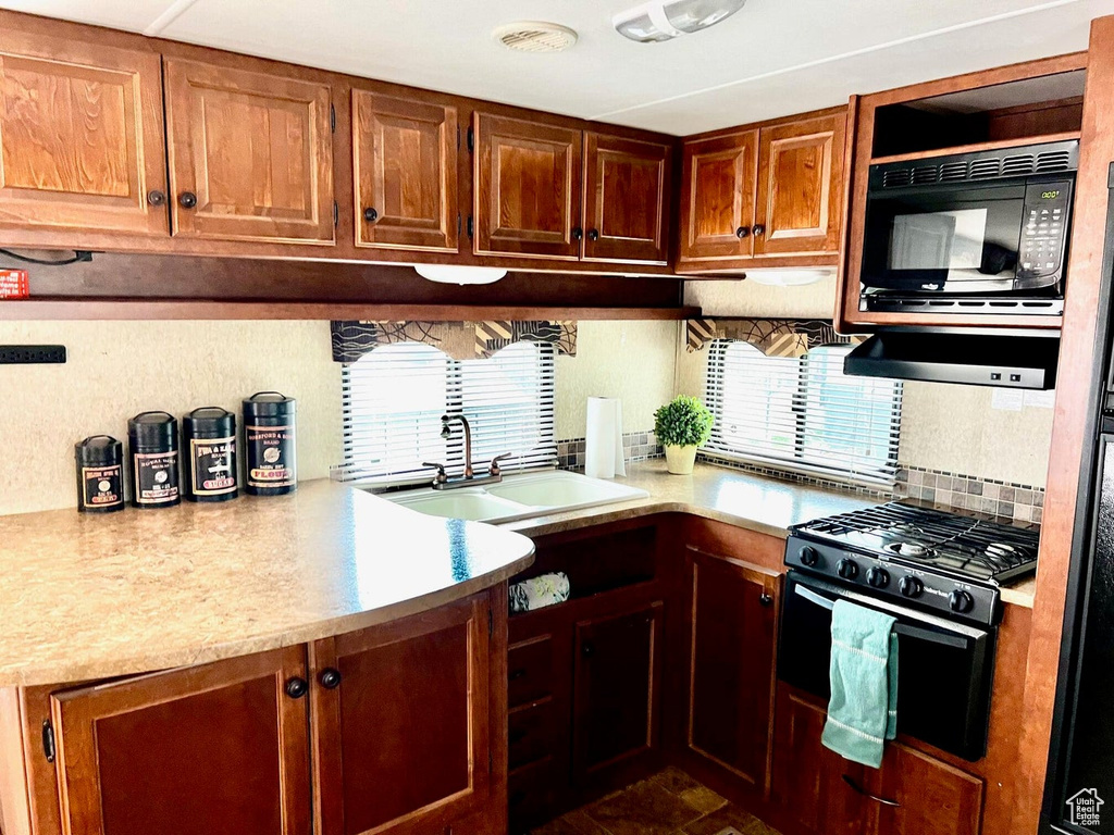 Kitchen with sink, black microwave, and gas stove