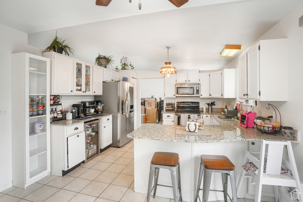 Kitchen with ceiling fan with notable chandelier, kitchen peninsula, appliances with stainless steel finishes, and wine cooler