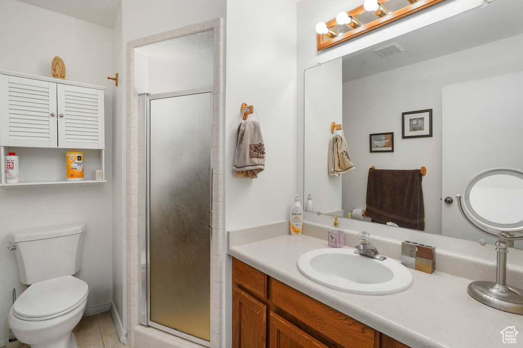 Bathroom featuring tile patterned flooring, an enclosed shower, vanity, and toilet