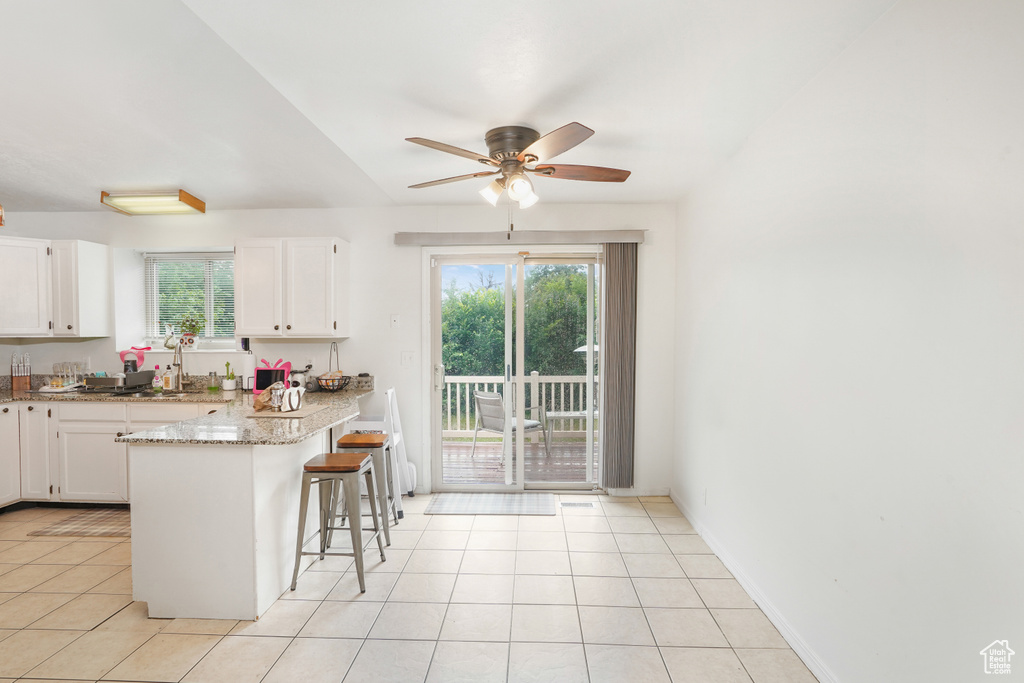 Kitchen featuring white cabinets, plenty of natural light, light tile patterned floors, and ceiling fan