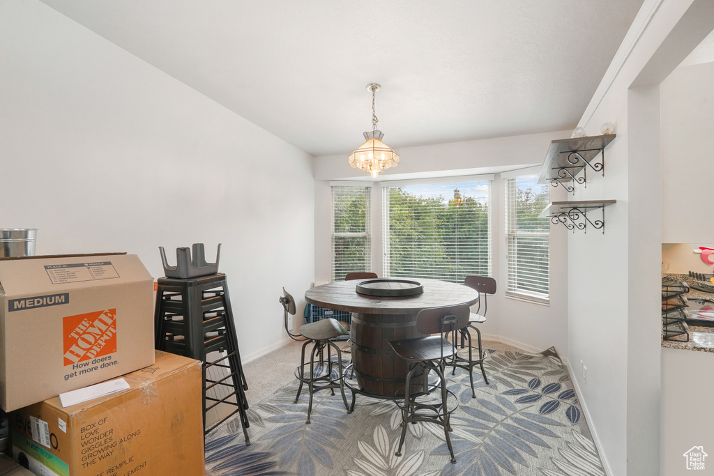 Carpeted dining room with an inviting chandelier