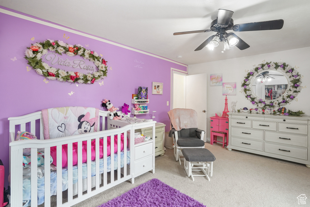 Bedroom featuring ceiling fan, a nursery area, and light carpet