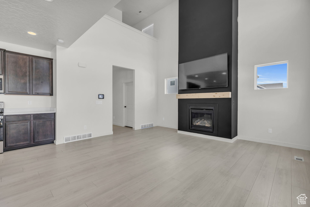 Unfurnished living room with light hardwood / wood-style flooring and a high ceiling