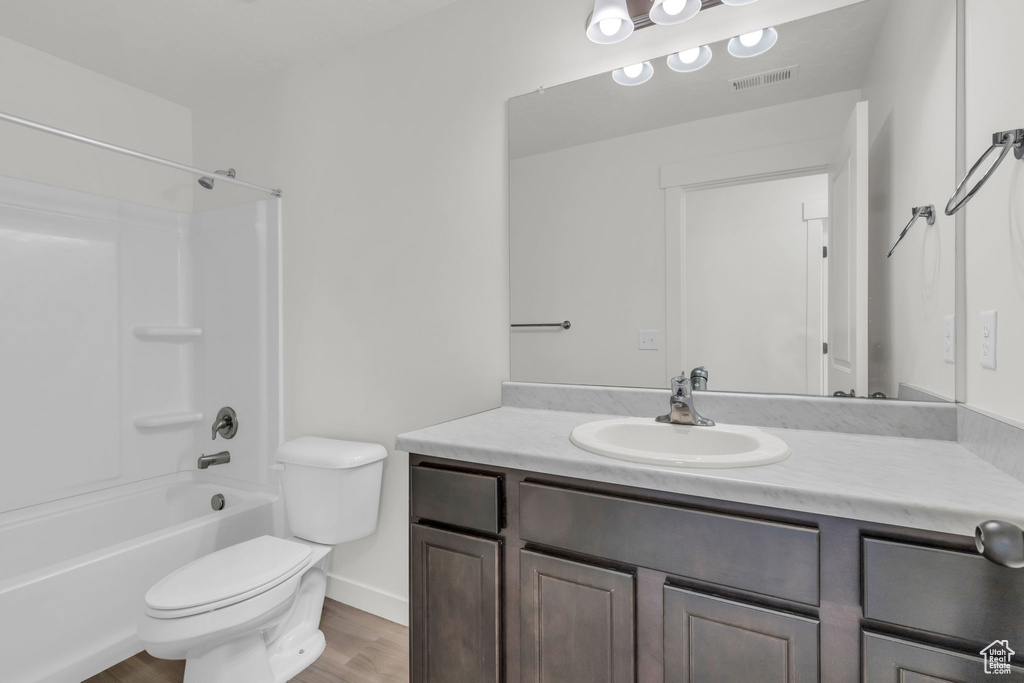 Full bathroom featuring hardwood / wood-style floors, shower / tub combination, vanity, and toilet