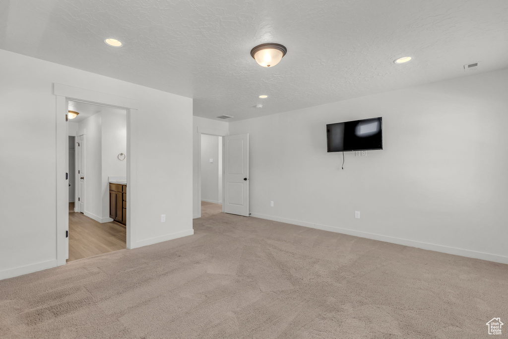 Empty room with a textured ceiling and light colored carpet