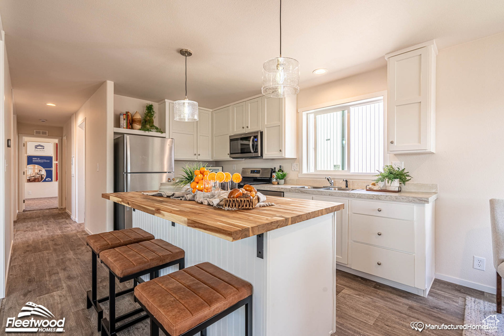 Kitchen with white cabinetry, stainless steel appliances, a center island, and butcher block counters