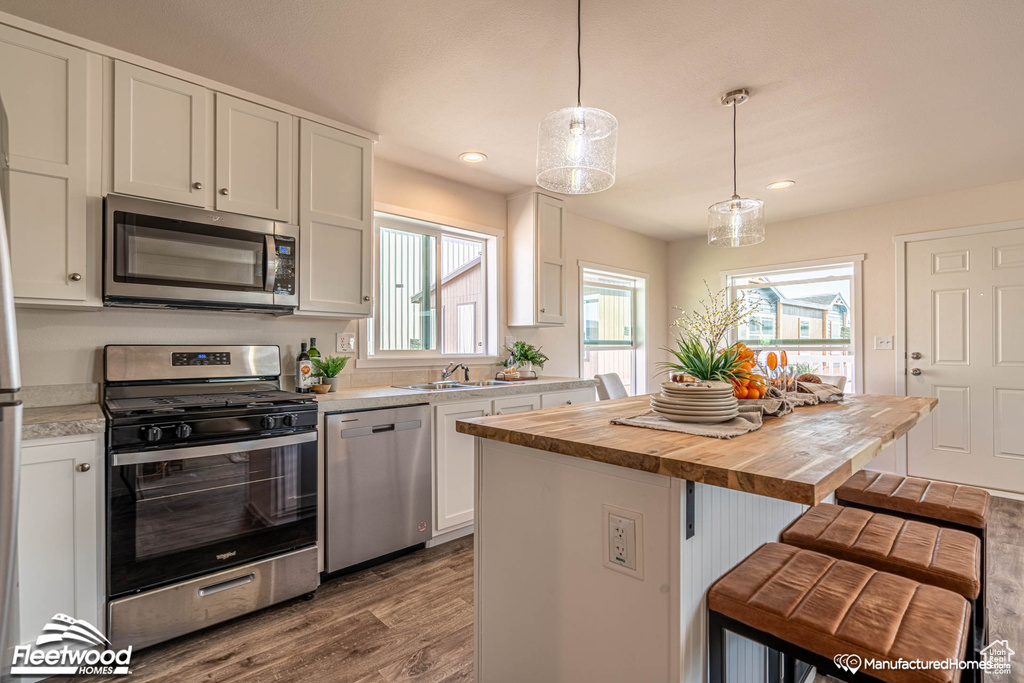 Kitchen featuring appliances with stainless steel finishes, white cabinets, wooden counters, and hardwood / wood-style flooring