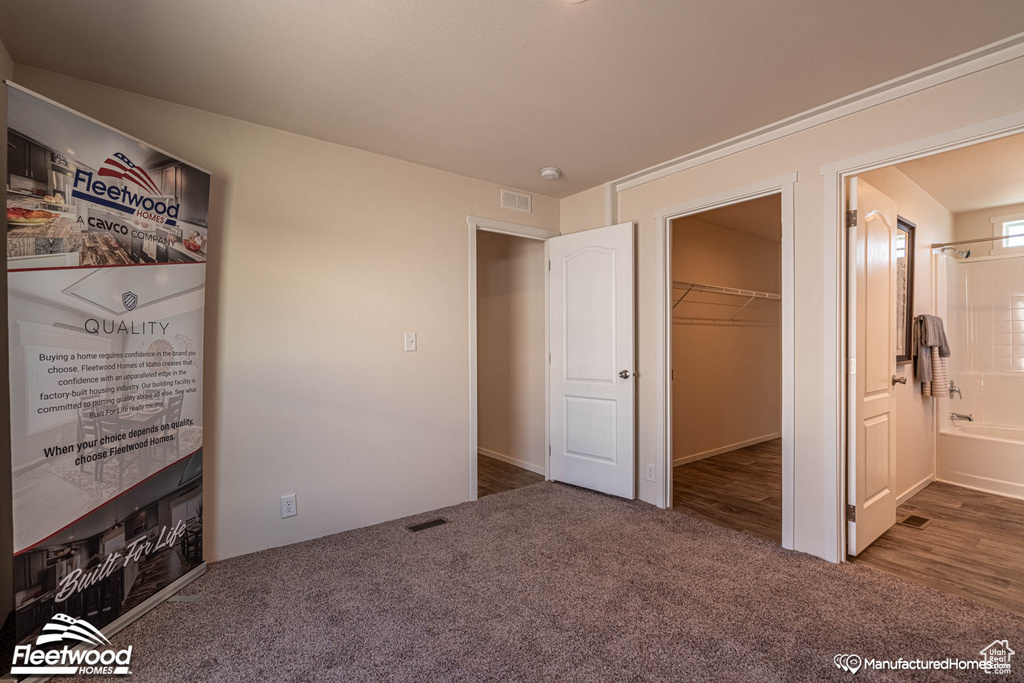 Unfurnished bedroom featuring ensuite bathroom, a closet, carpet flooring, and a spacious closet