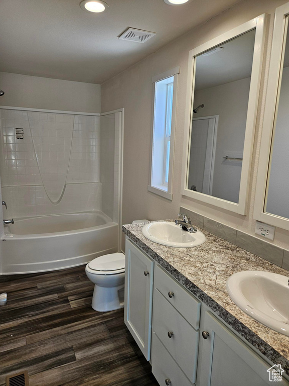 Full bathroom with double vanity,  shower combination, toilet, and hardwood / wood-style floors