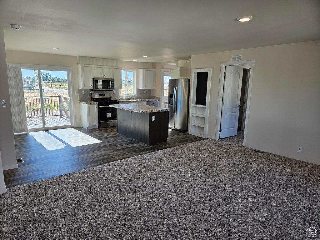 Kitchen with stainless steel appliances, dark hardwood / wood-style floors, a kitchen island, sink, and white cabinetry