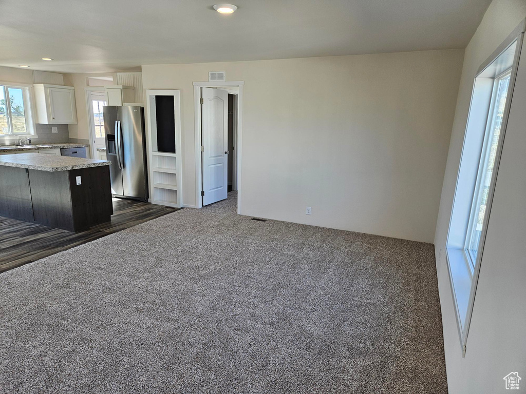 Kitchen featuring dark wood-type flooring, a kitchen island, sink, white cabinetry, and stainless steel fridge